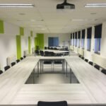 Spacious indoor meeting room with modern furniture and large windows.